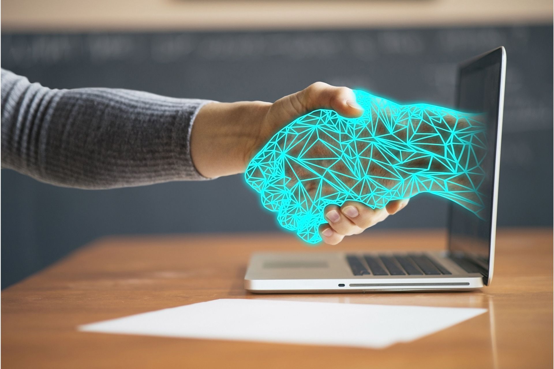 handshake between person and digital hand coming out of a laptop screen