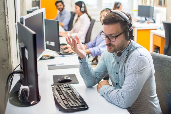 addetto al callcenter durante telefonata di assistenza al computer con cuffie e microfono