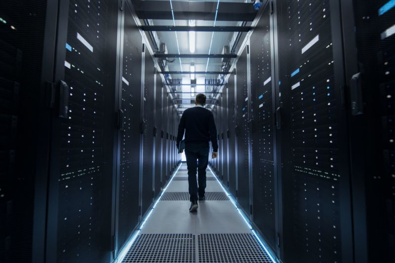 technician in data center walking in server room with all racks connected